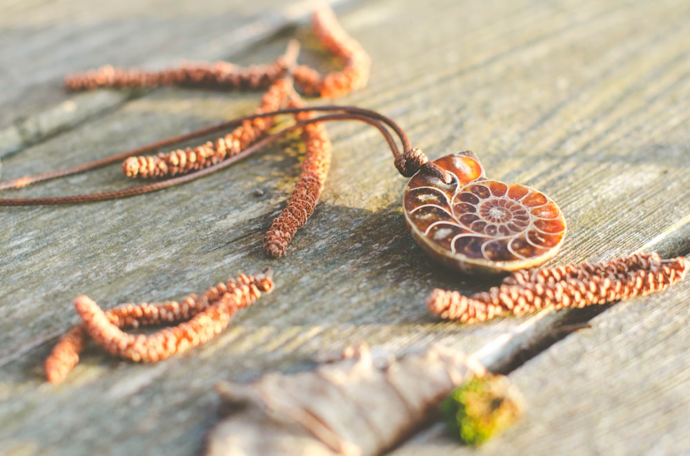 a necklace with a flower on it sitting on a wooden surface