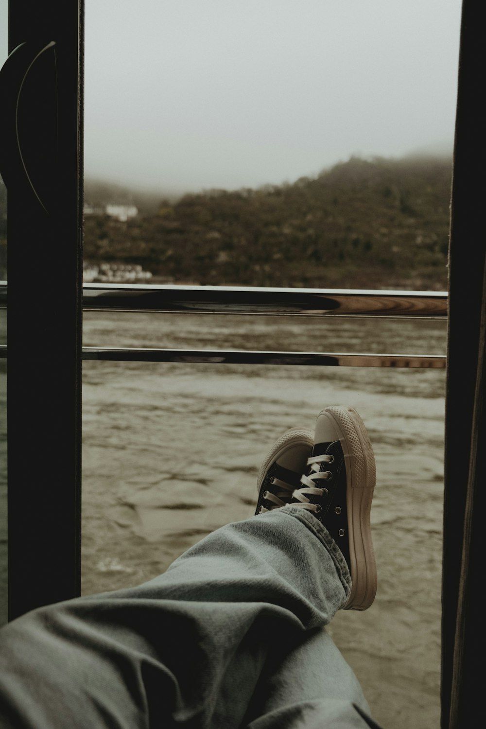 a person's feet in a pair of sneakers looking out a window
