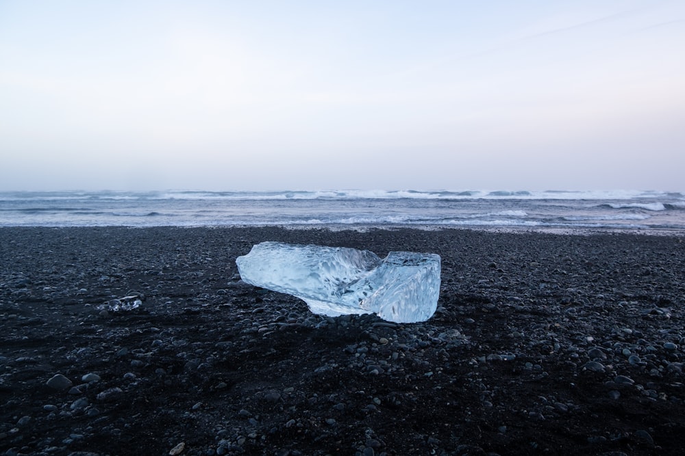 a piece of ice sitting on top of a black beach