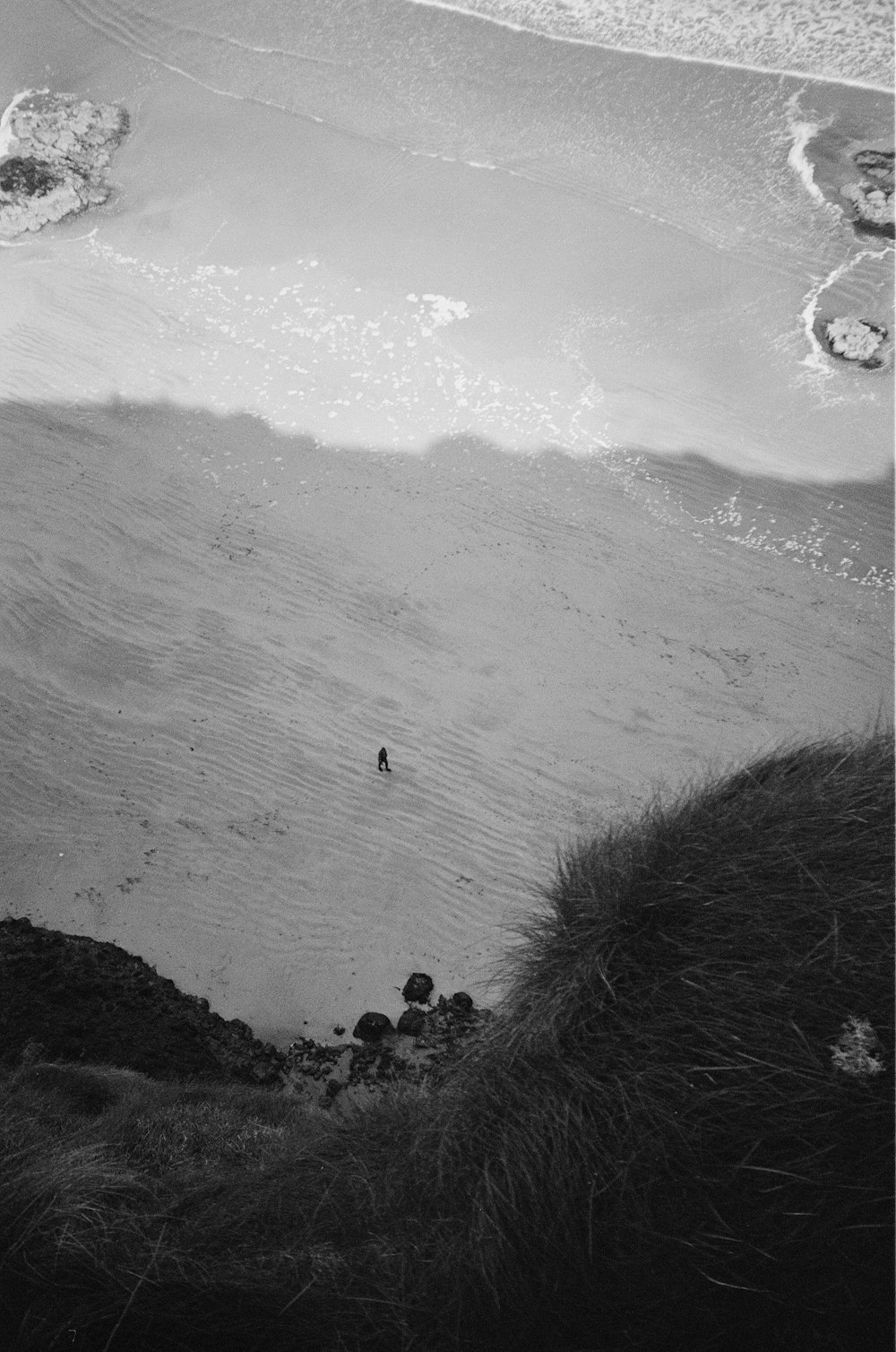 a black and white photo of a person walking on a beach