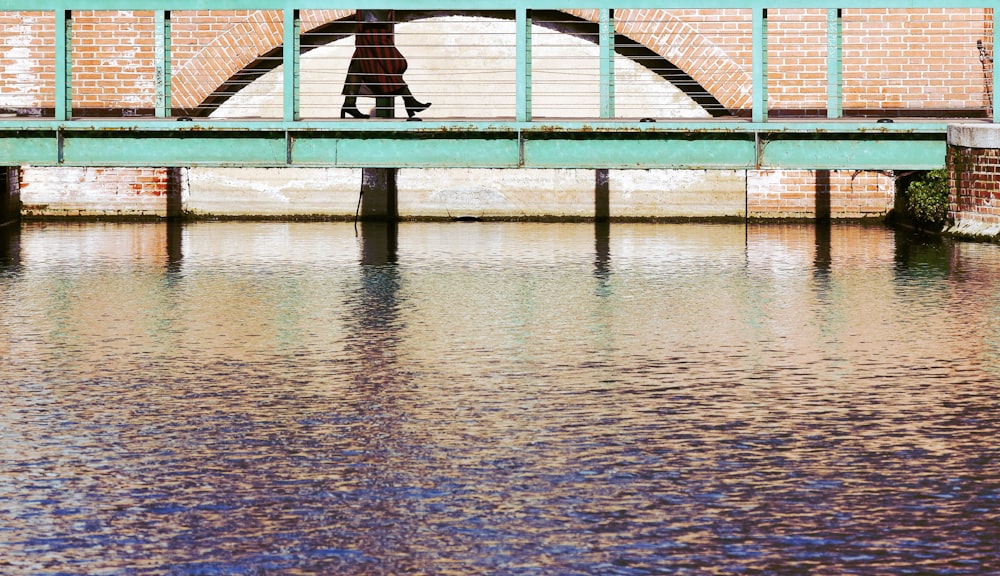 a person walking across a bridge over a body of water