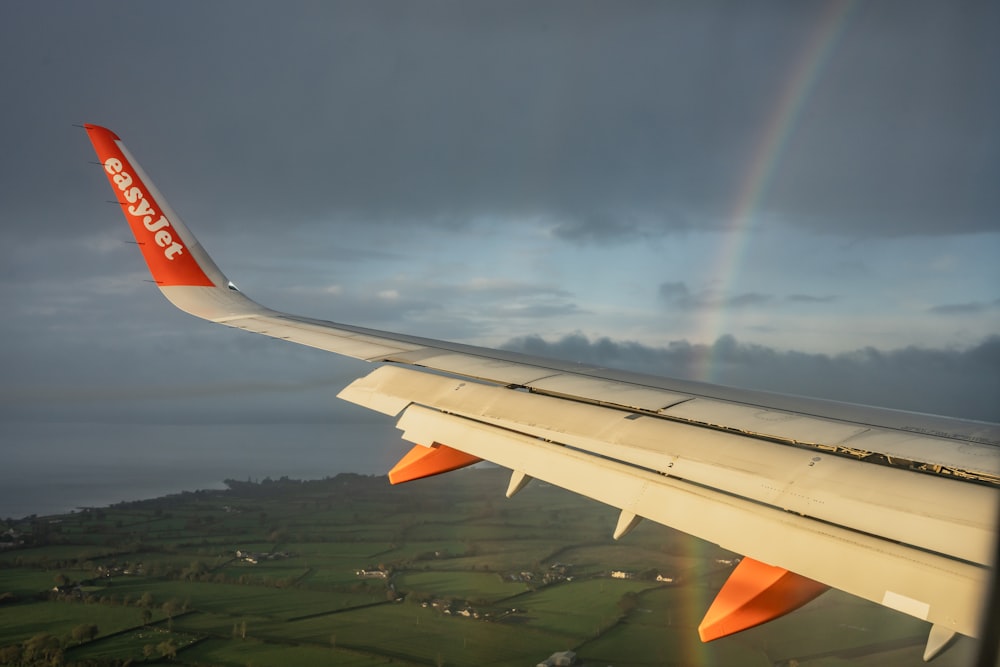 an airplane wing with a rainbow in the background