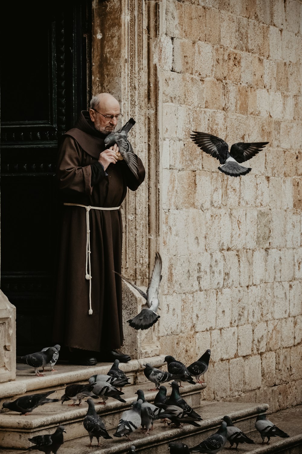 a man standing in front of a bunch of pigeons