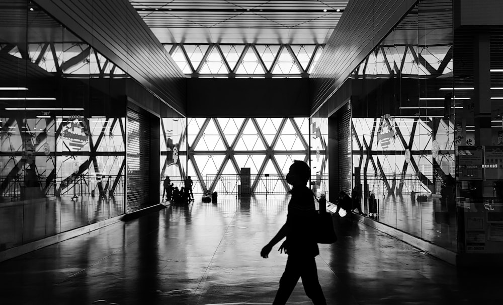 a black and white photo of a person walking through a building