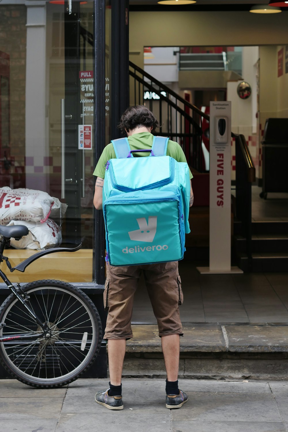 a person with a blue backpack standing on a sidewalk