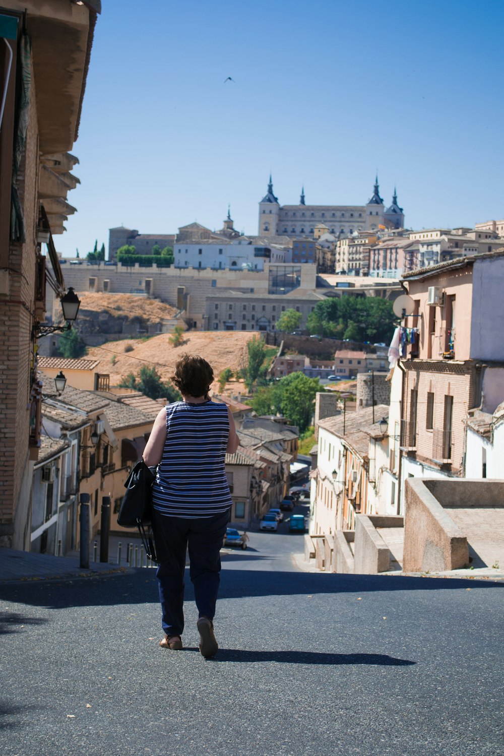 a woman walking down a street with buildings in the background