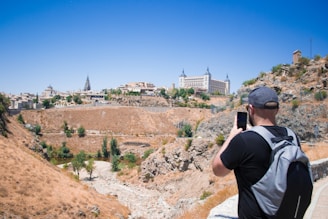 a man taking a picture of a city from a hill