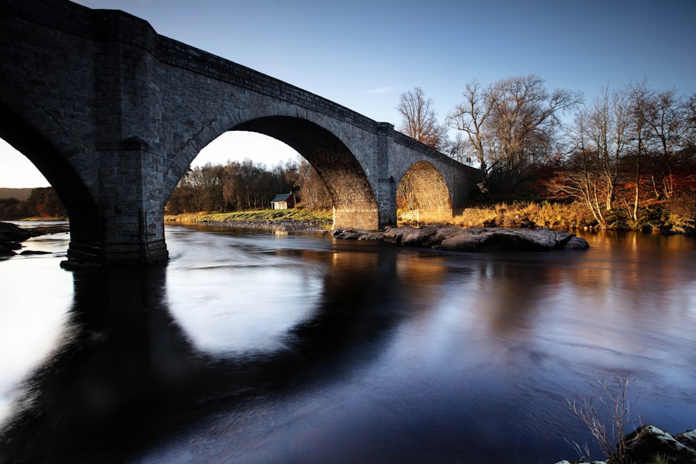 an old stone bridge over a river in the fall