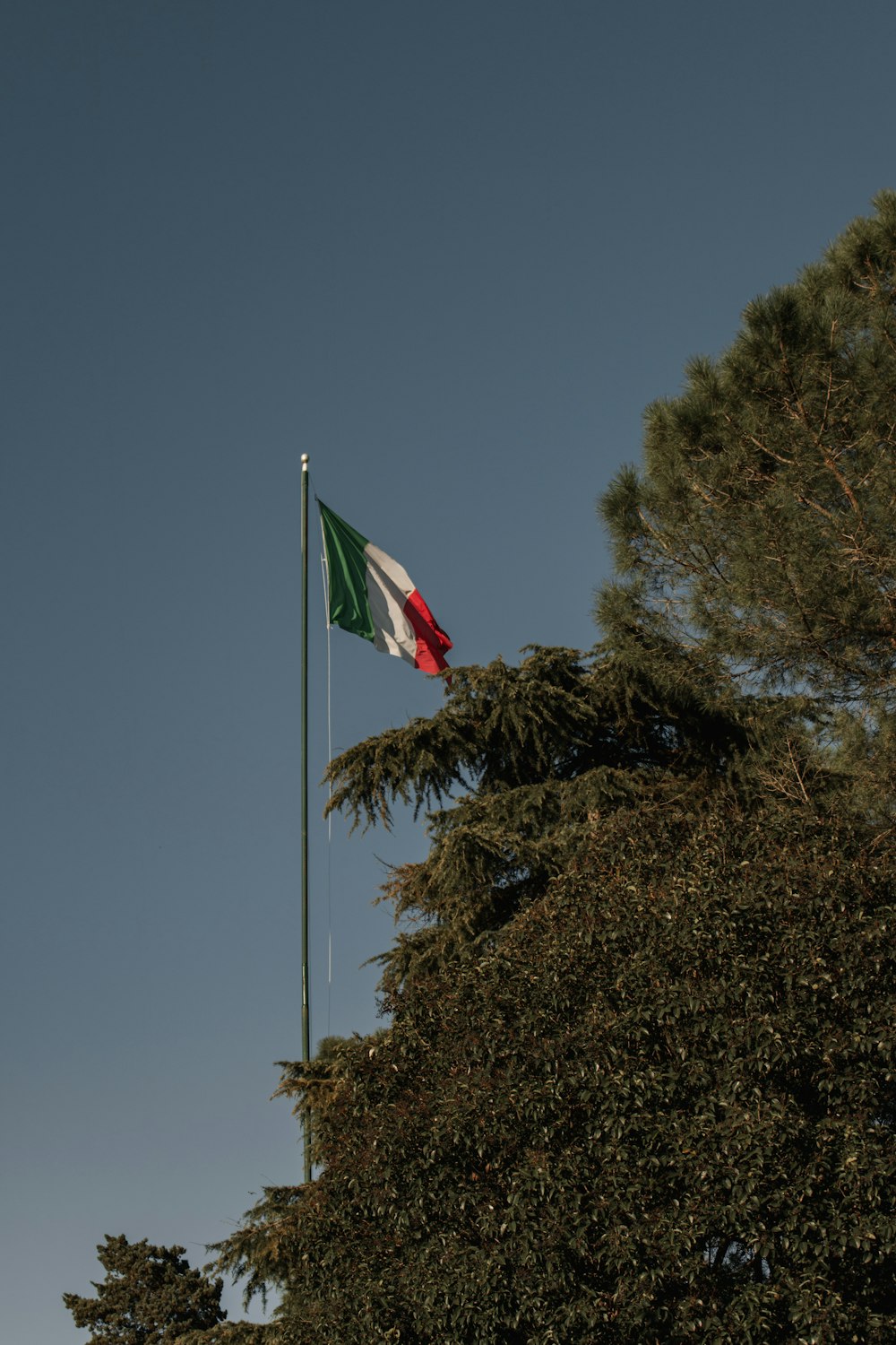 the flag of italy is flying high in the sky