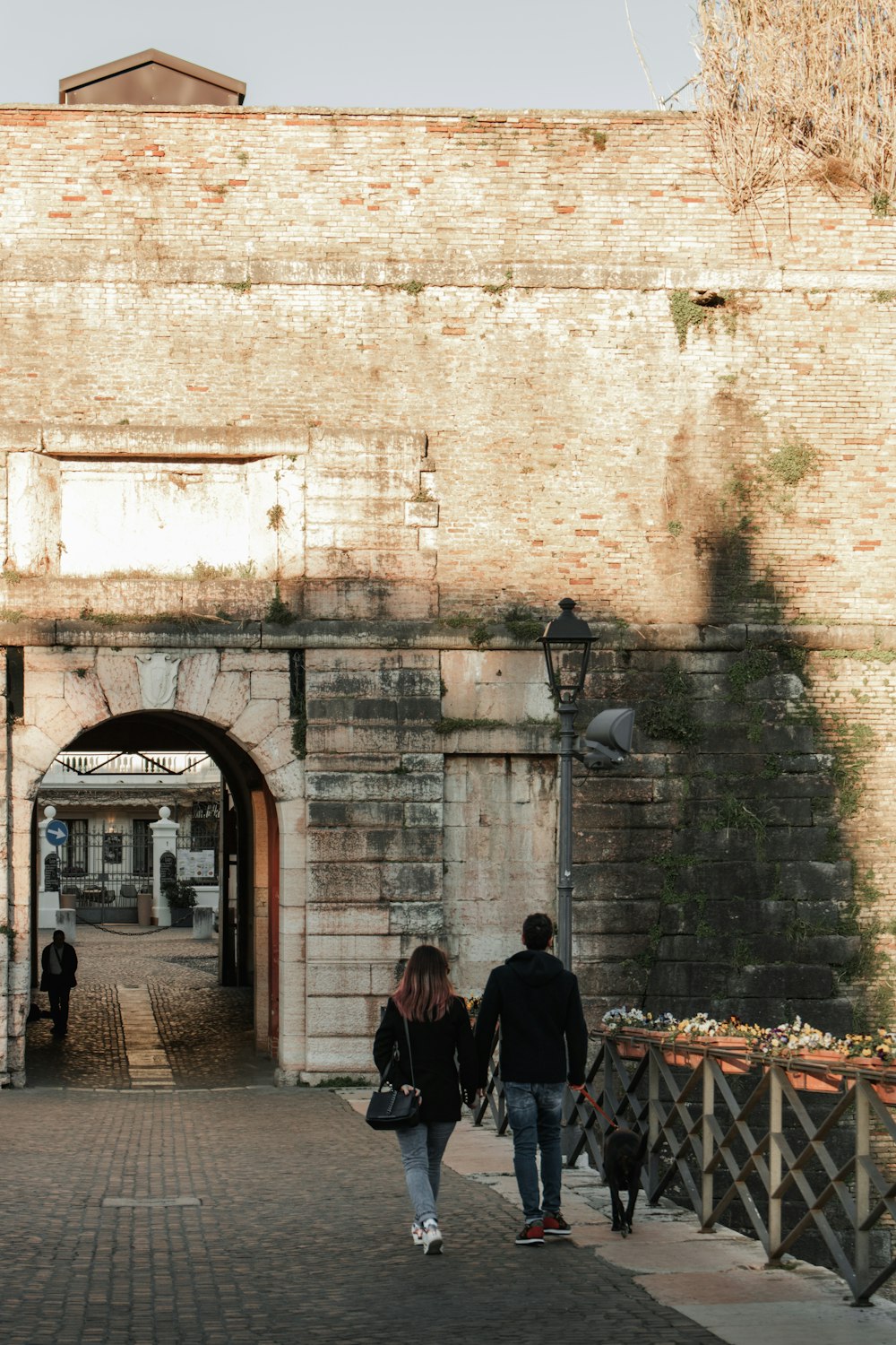 a couple of people walking down a brick walkway