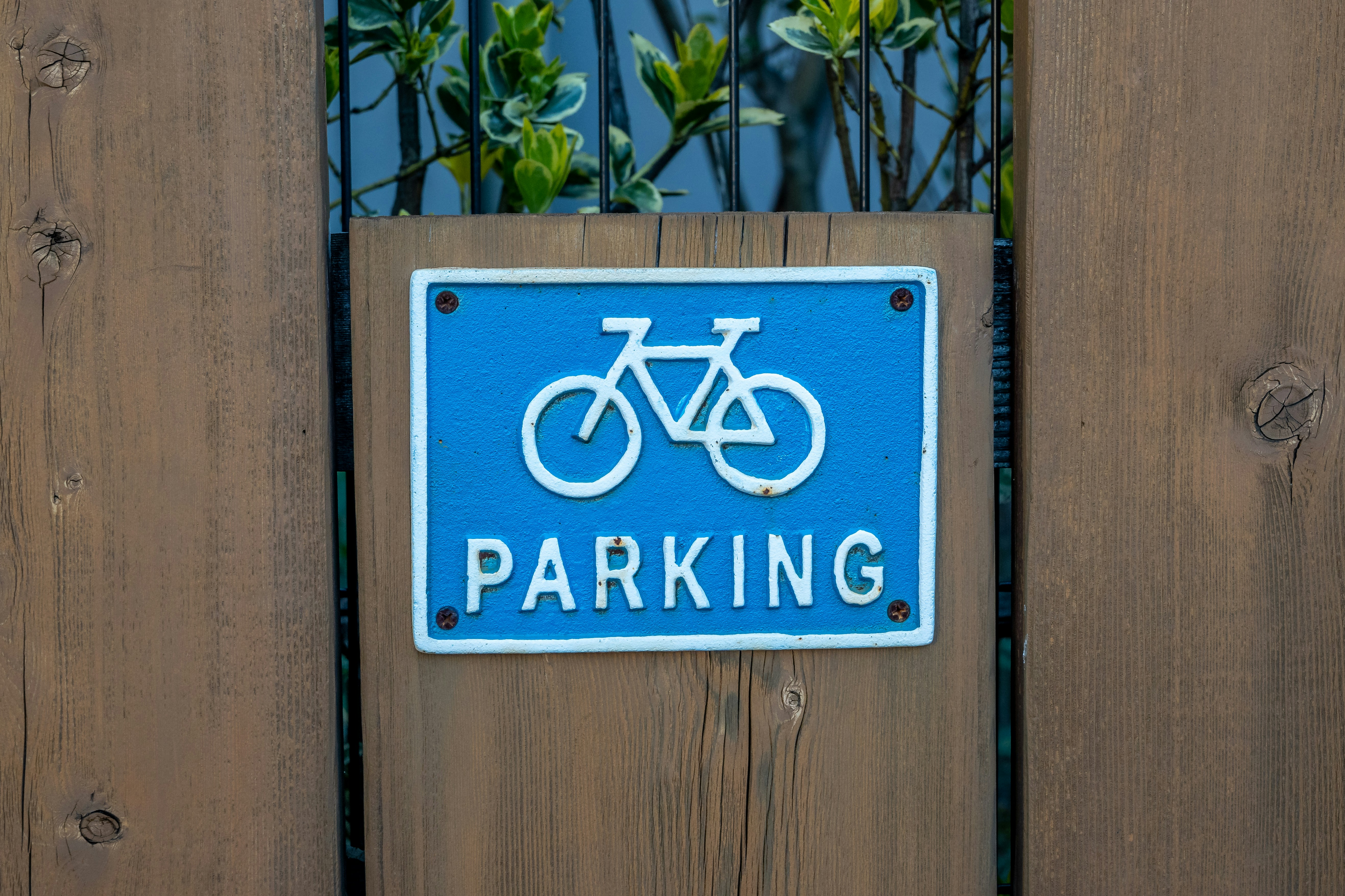 a blue parking sign mounted to a wooden fence