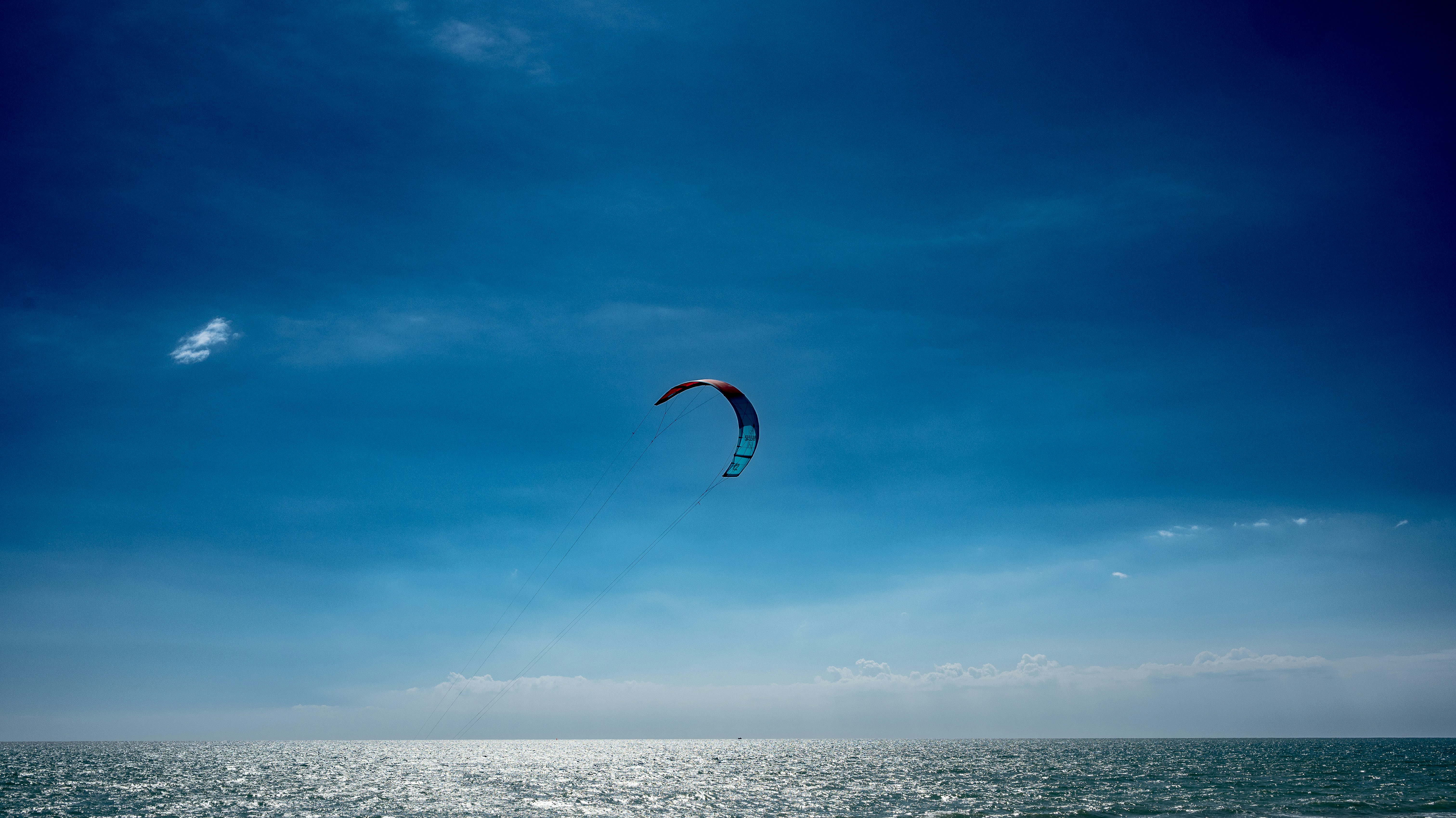 a kite flying over the ocean on a sunny day