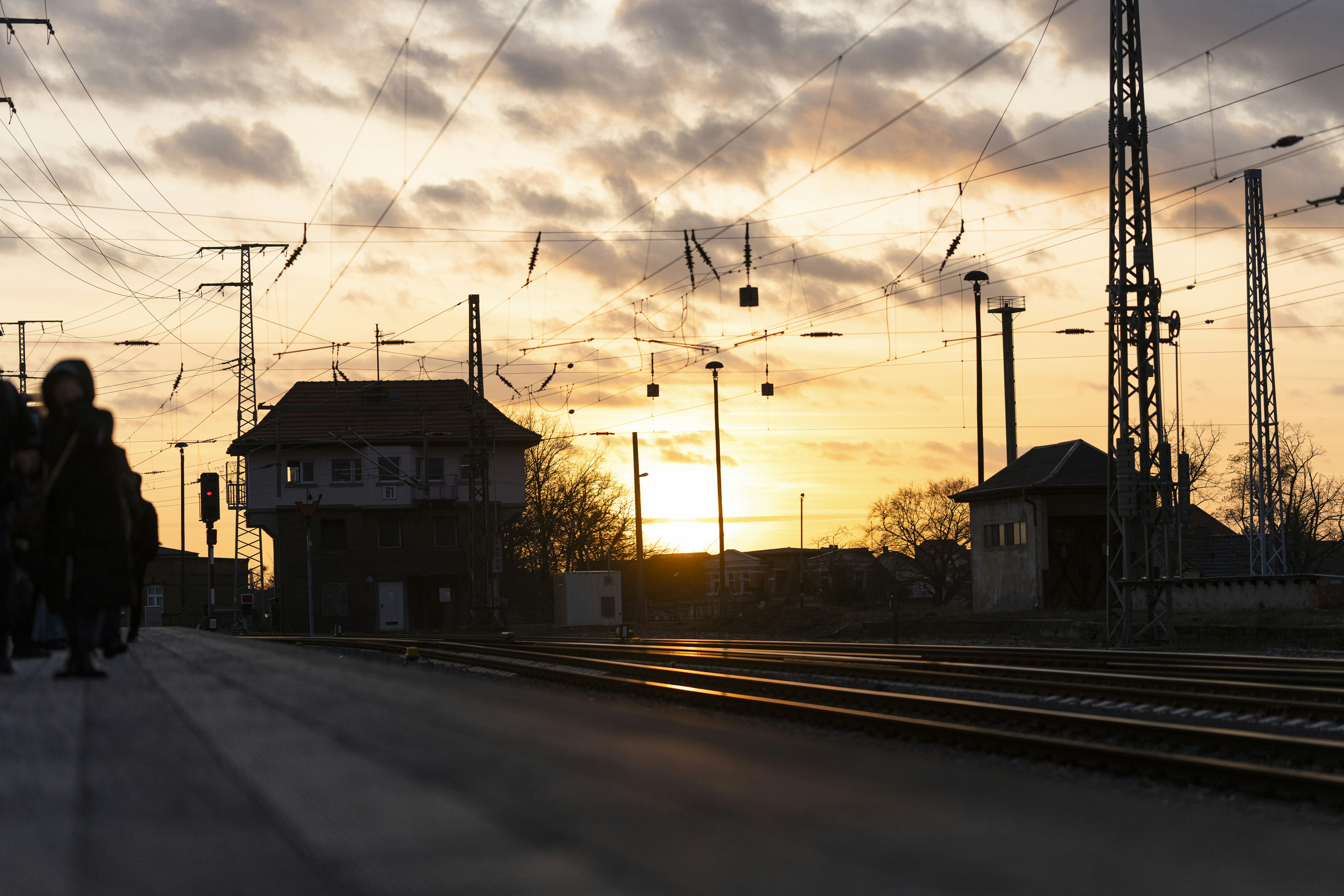 a group of people walking down a train track, Sunset on a train journey in Germany