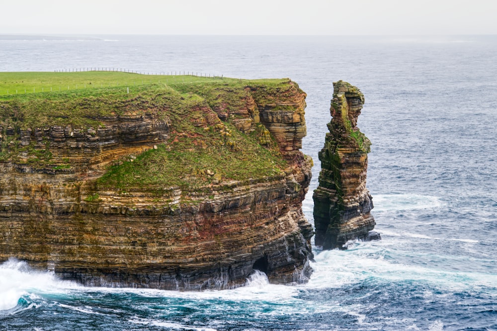 a large cliff with a grassy area on top of it