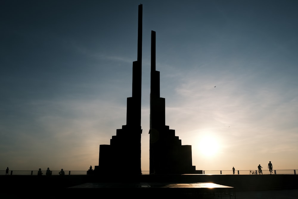 the sun is setting behind a tall monument