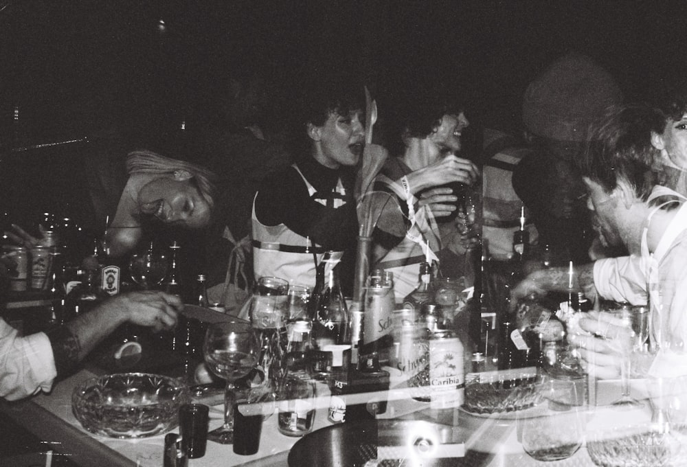 a group of men standing around a table filled with bottles and glasses
