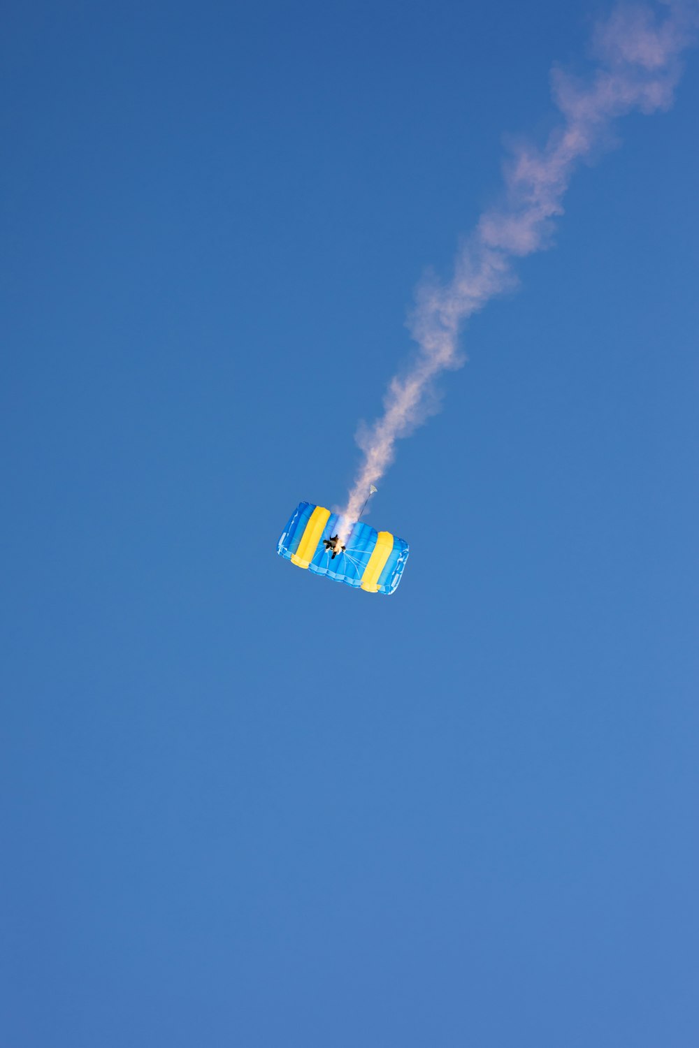 a blue and yellow plane flying through a blue sky