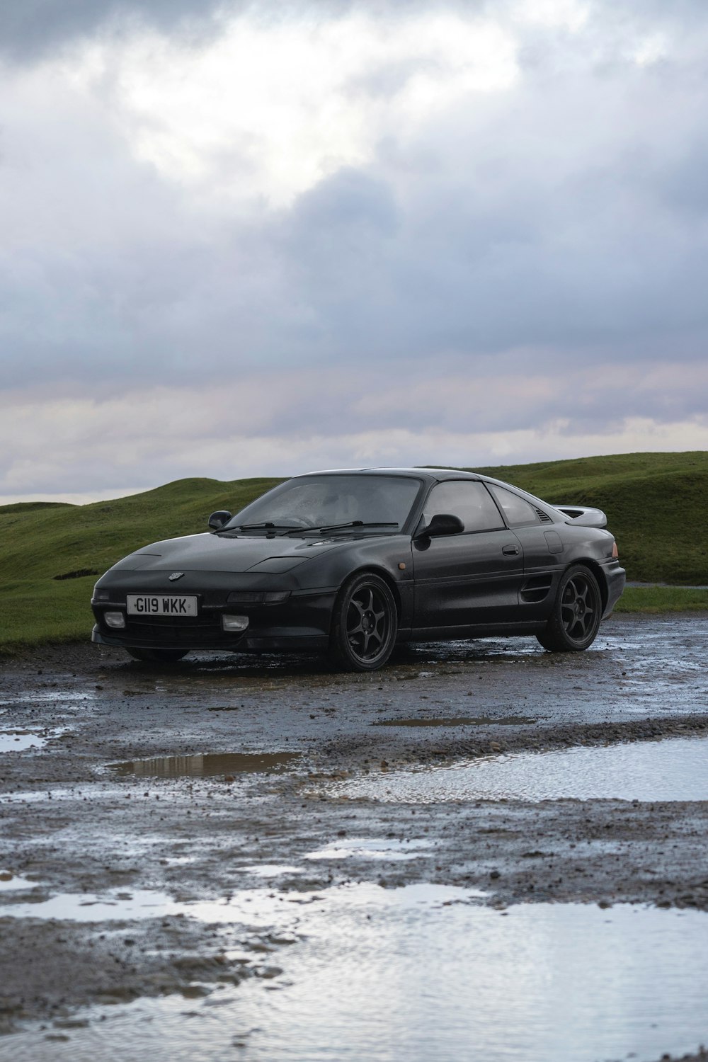 a black sports car parked on a wet parking lot