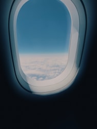 an airplane window with a view of the clouds below