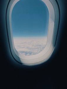 an airplane window with a view of the clouds below