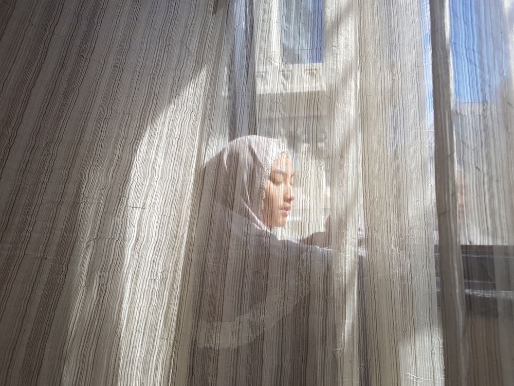 a woman in a headscarf looking out of a window