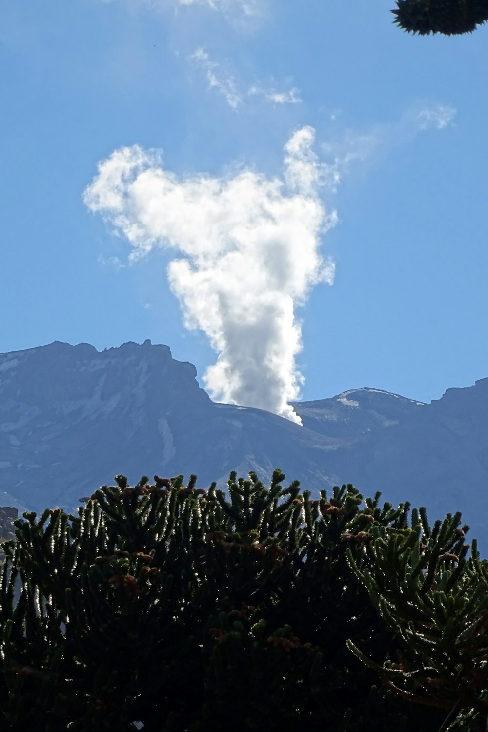 a plume of smoke coming out of the top of a mountain