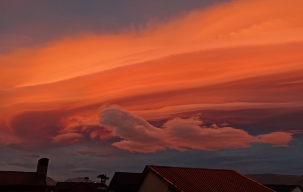 a red cloud is in the sky above some houses