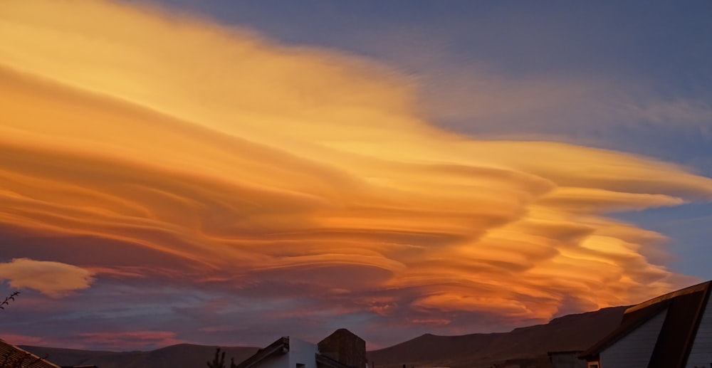 a large cloud is in the sky over some houses