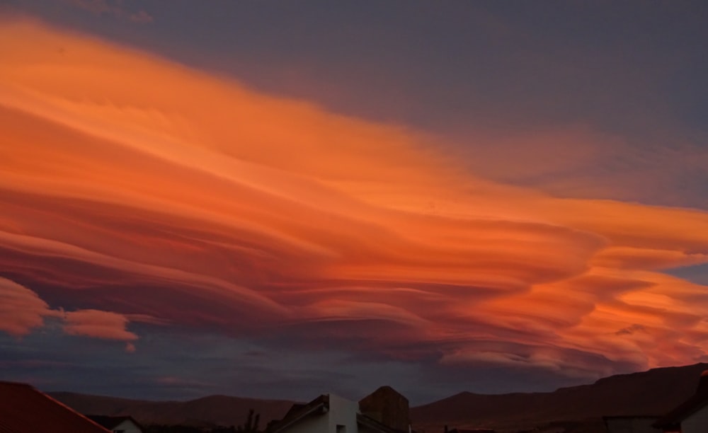 a very colorful cloud in the sky over some houses