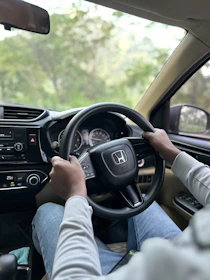 a person driving a car with a steering wheel