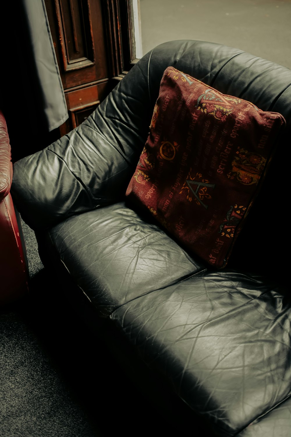 a black leather couch with a red pillow