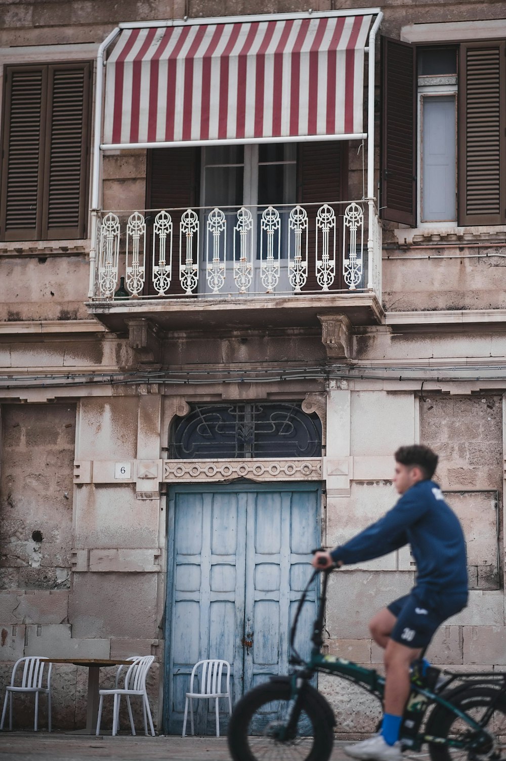 a man riding a bike past a tall building