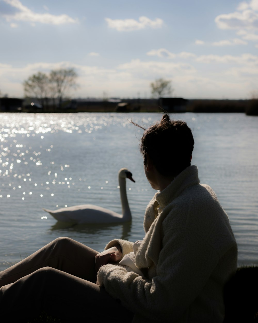 una mujer sentada en un banco junto a un cisne