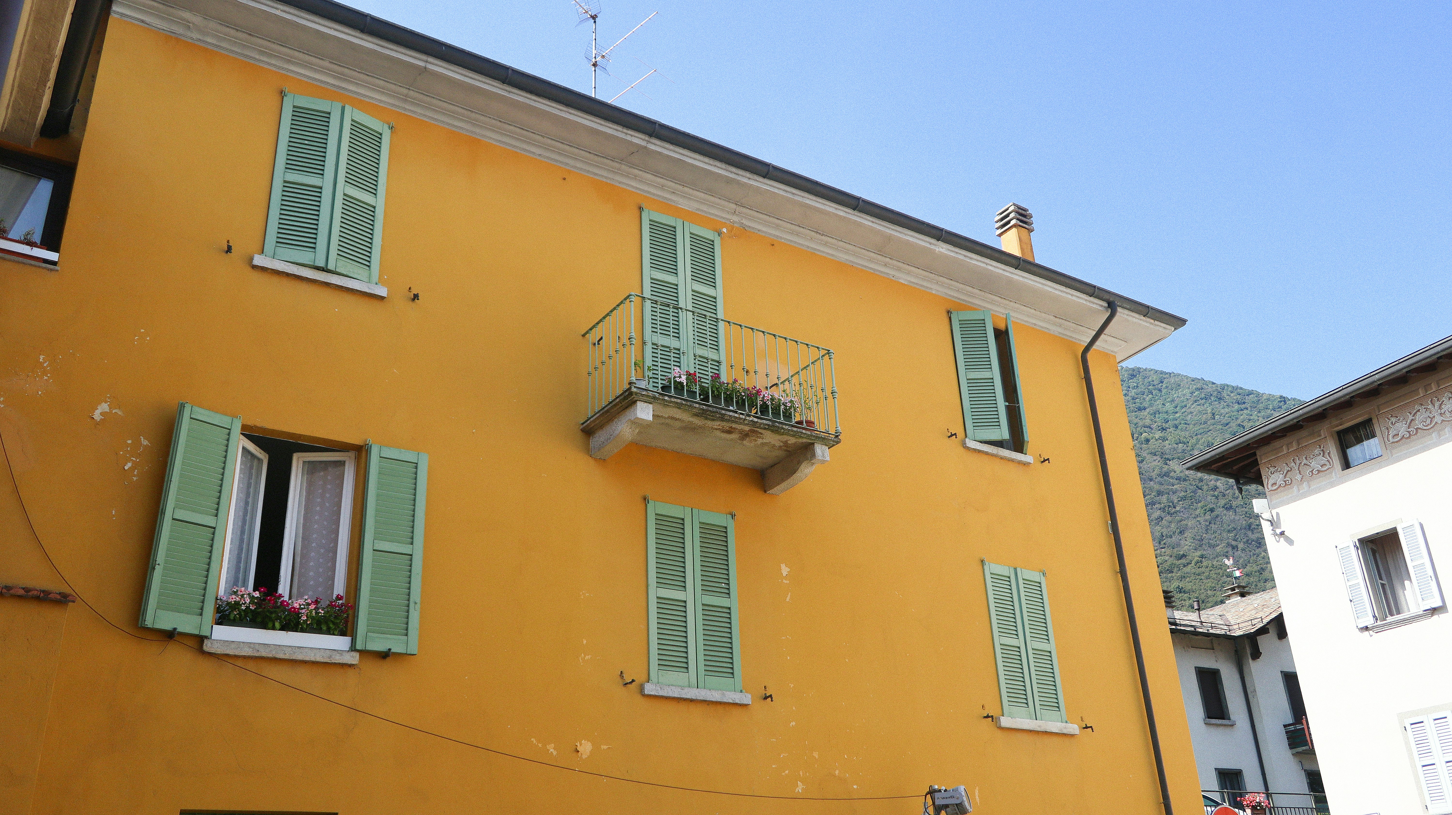a yellow building with green shutters and a balcony