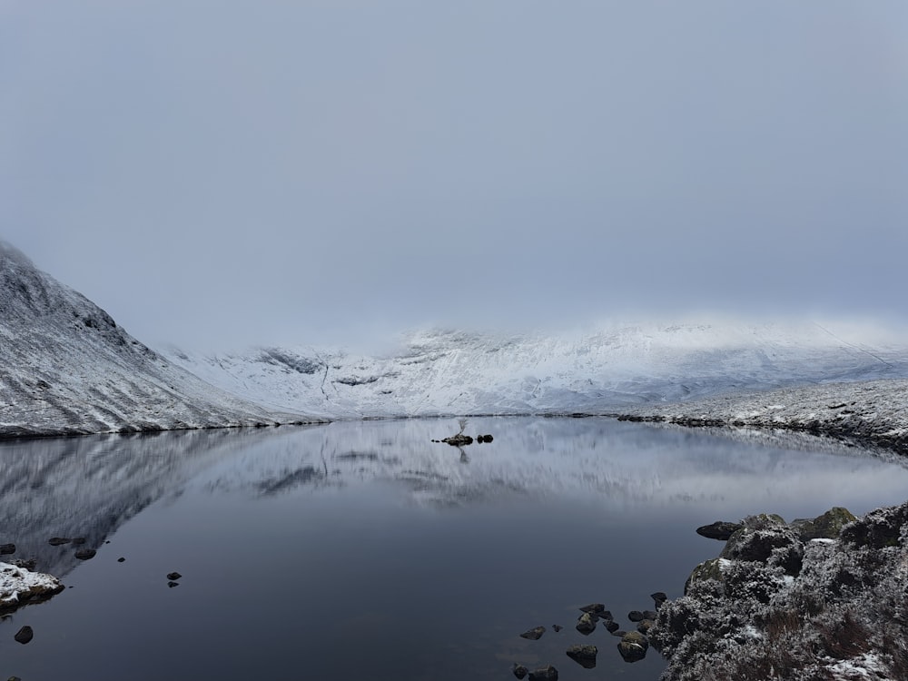 a large body of water surrounded by snow covered mountains