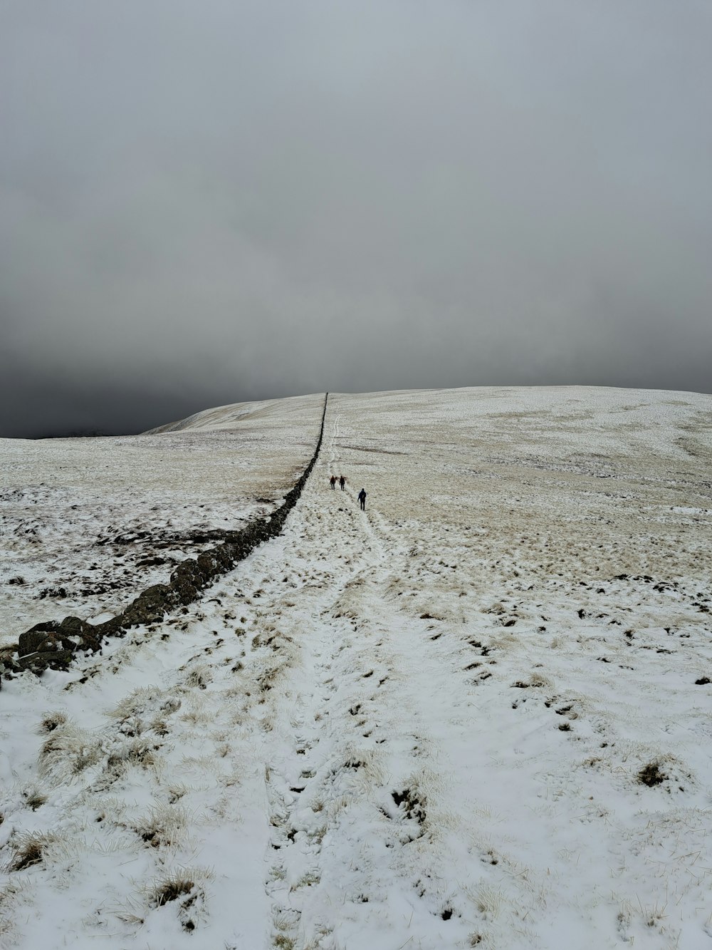 a couple of people walking across a snow covered field