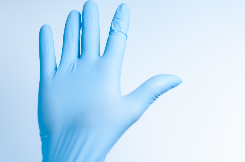 a hand wearing a blue latex glove with one hand raised up