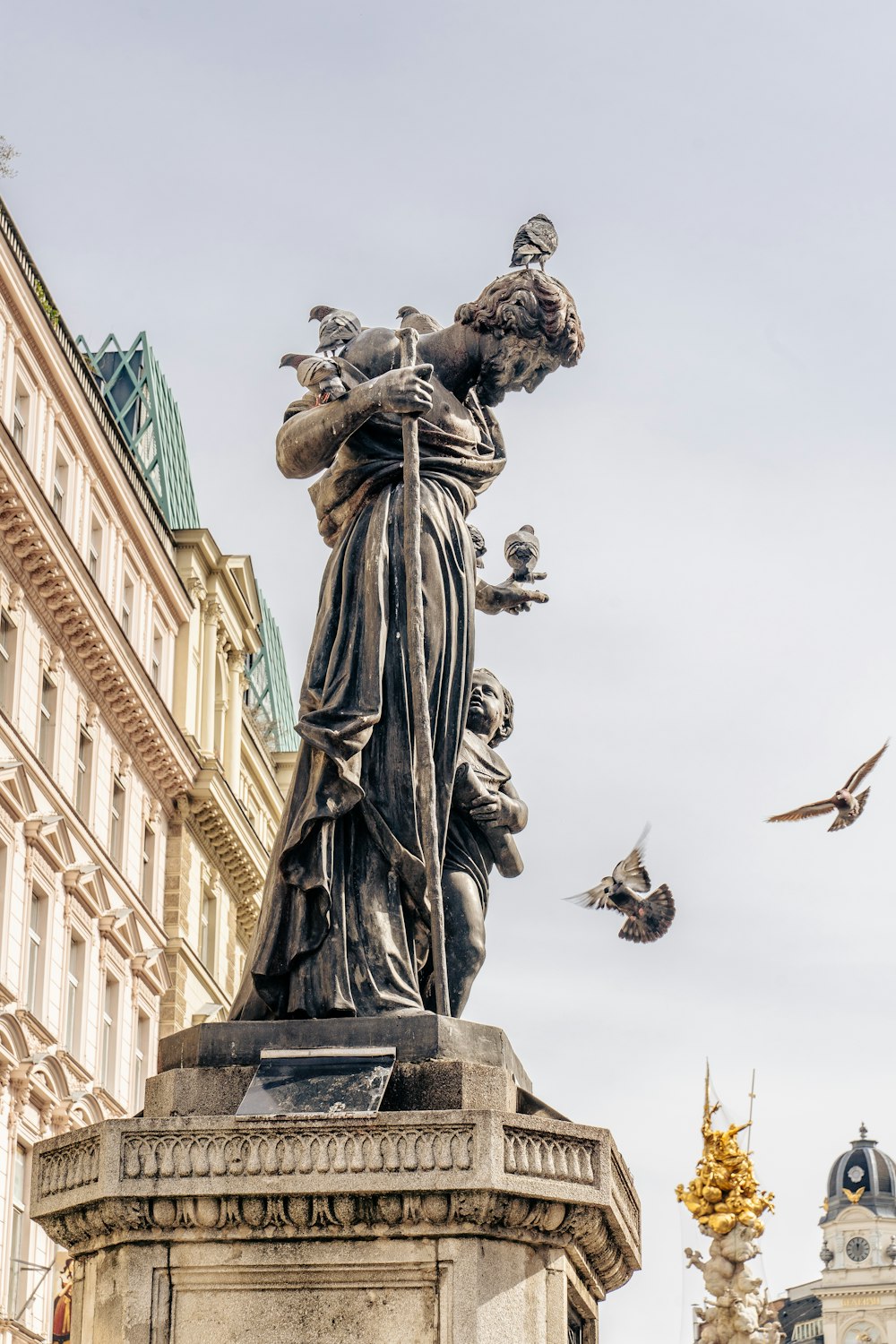 a statue of a woman with birds flying around her
