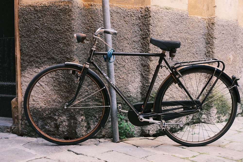 a bicycle parked next to a pole on a cobblestone street