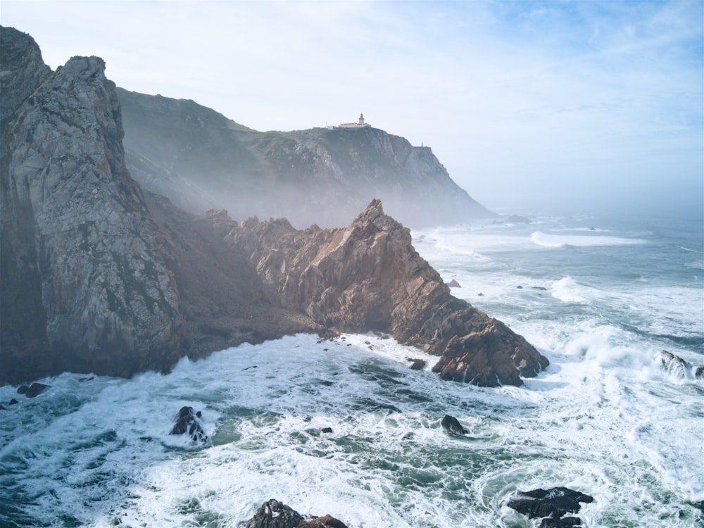 a group of people standing on top of a cliff near the ocean