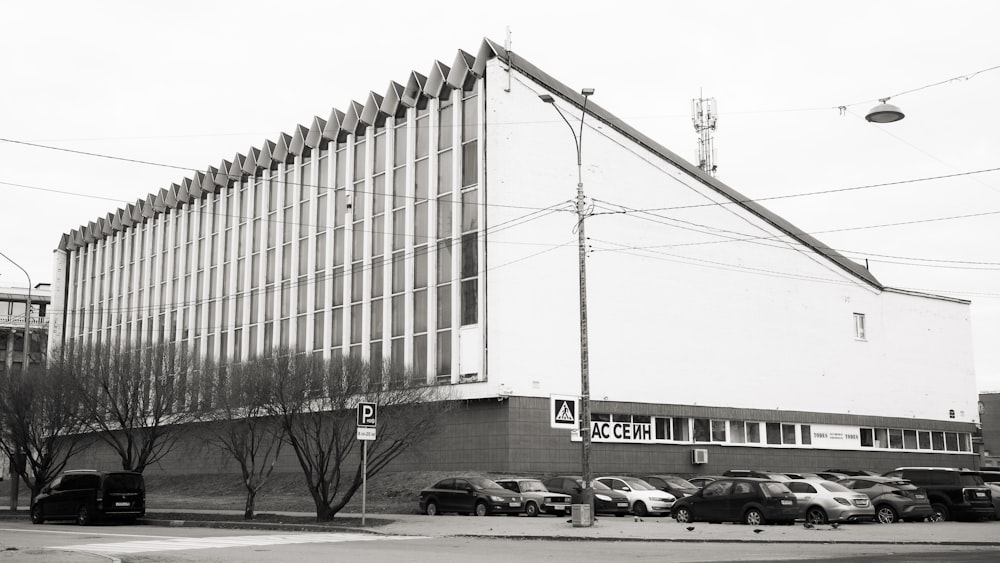 a black and white photo of a building with cars parked in front of it