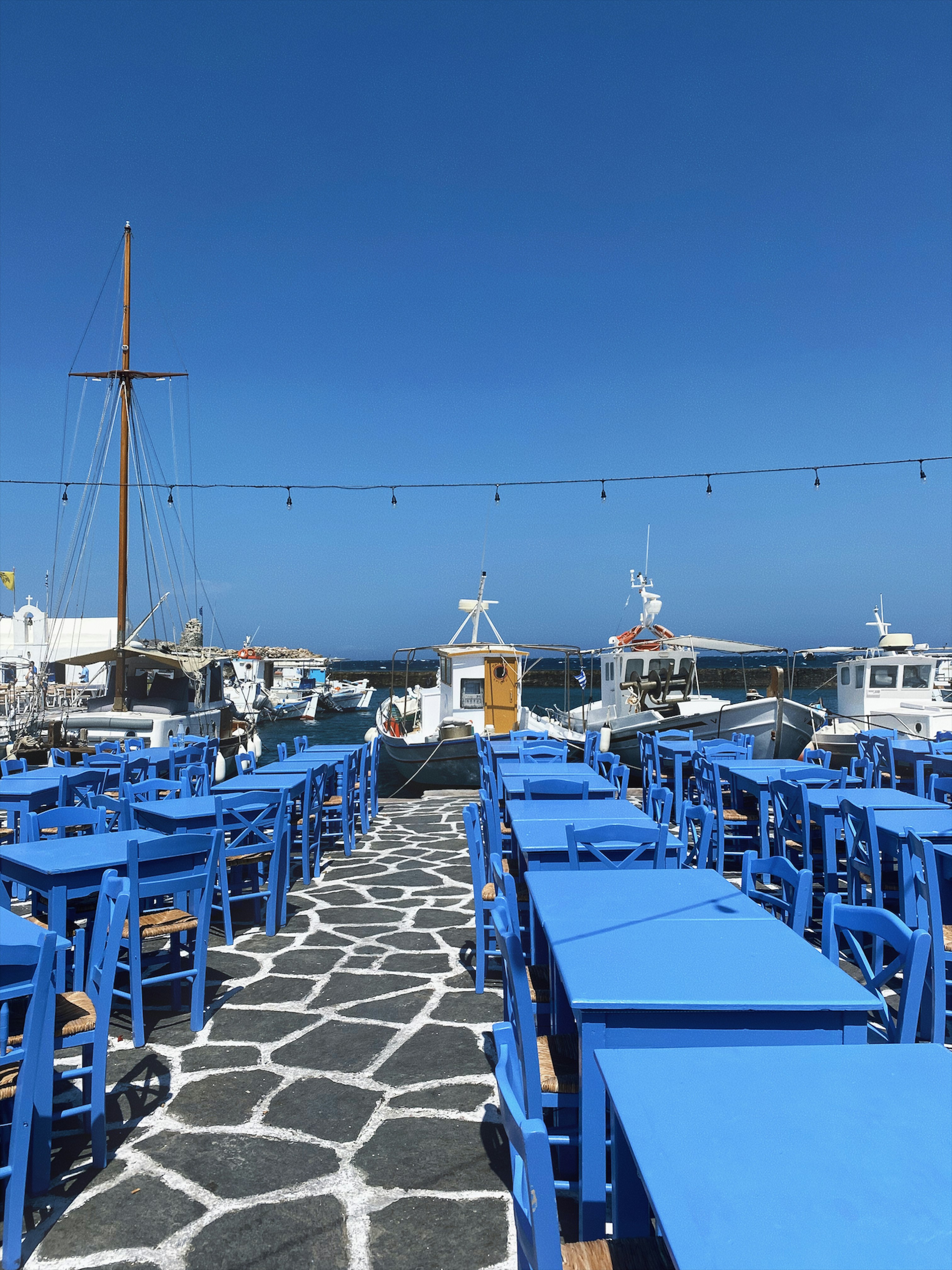 a row of blue tables sitting on top of a stone walkway