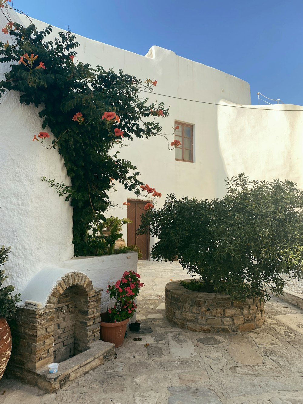 a white building with a stone fireplace and potted plants