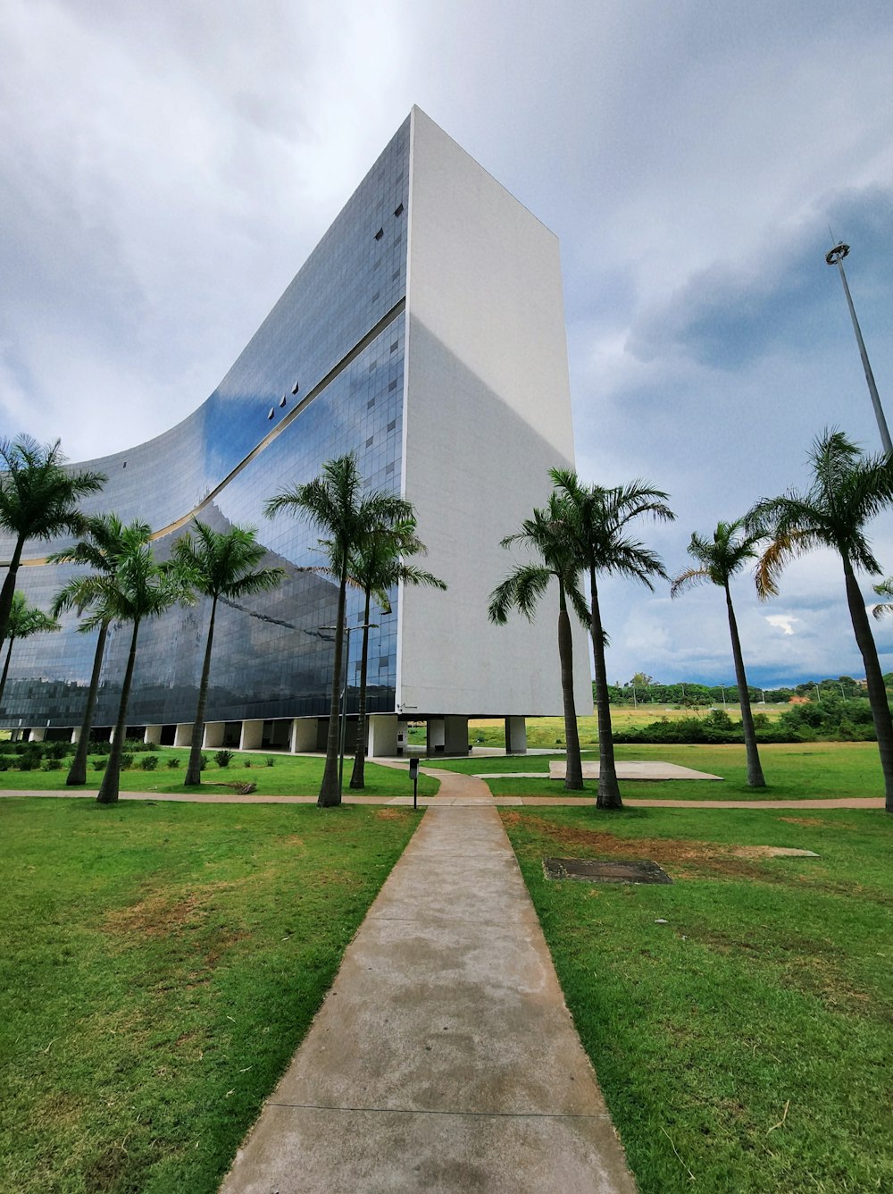 a very tall building sitting in the middle of a lush green field