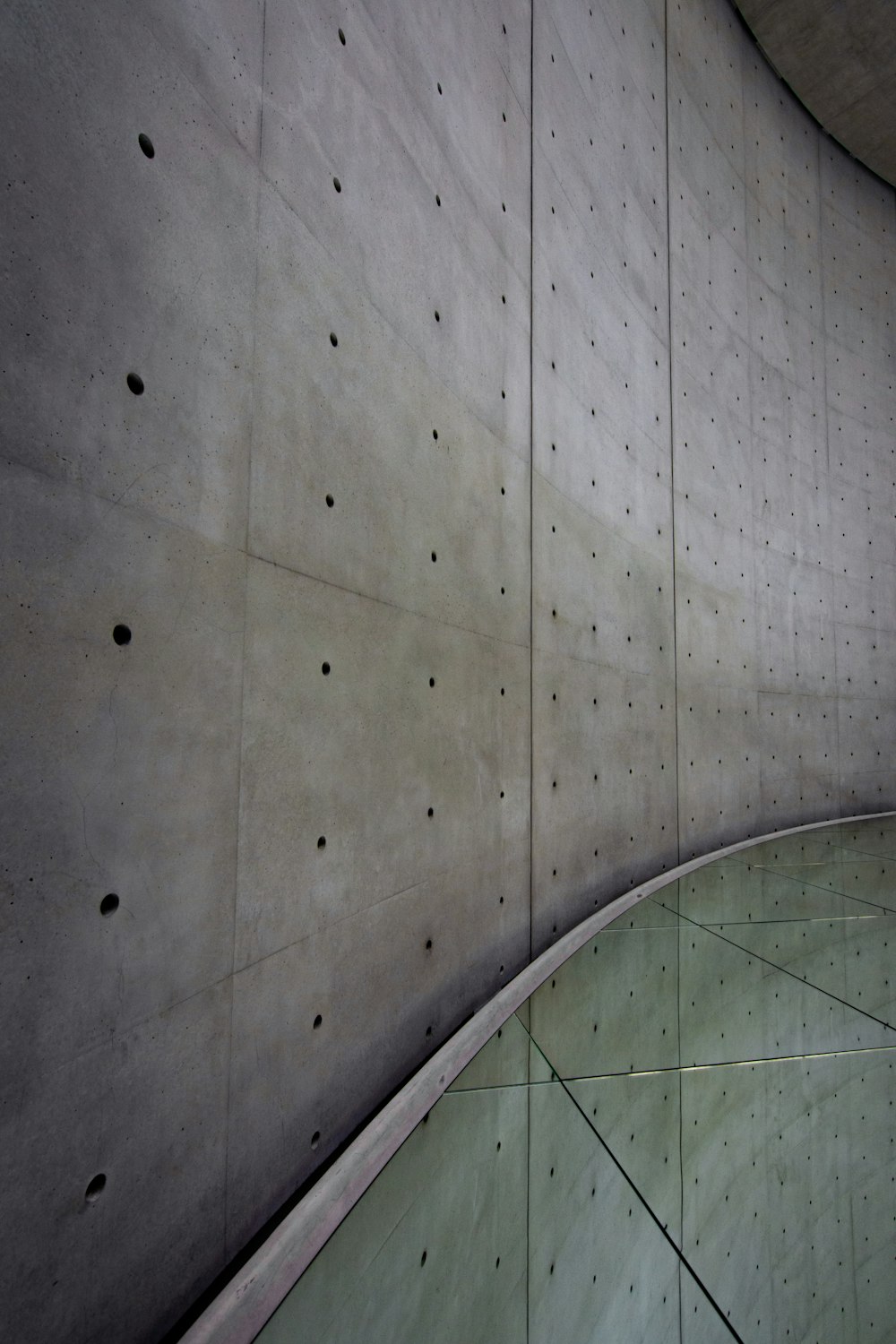 a curved concrete wall with holes in it