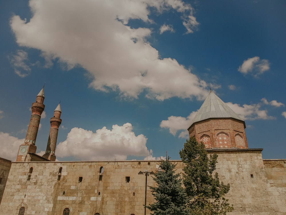 a large brick building with two towers and a sky background