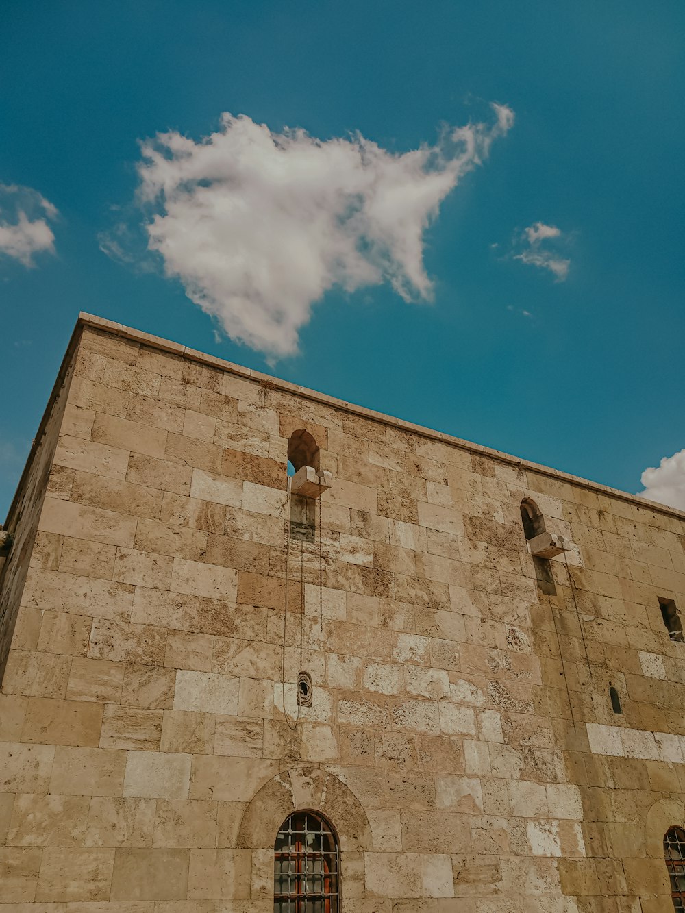 a tall brick building with two windows and a sky background