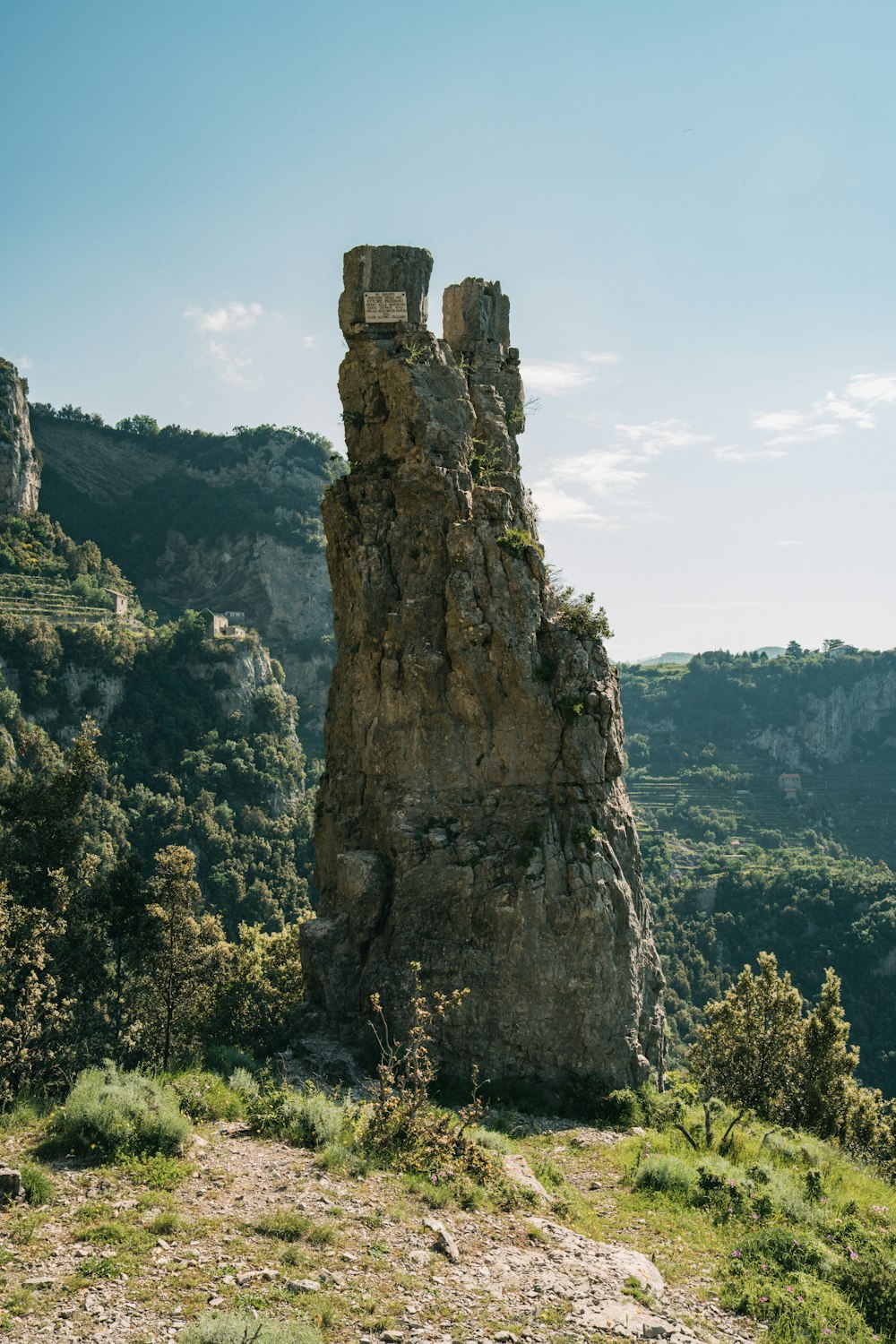 a tall rock tower sitting on top of a lush green hillside