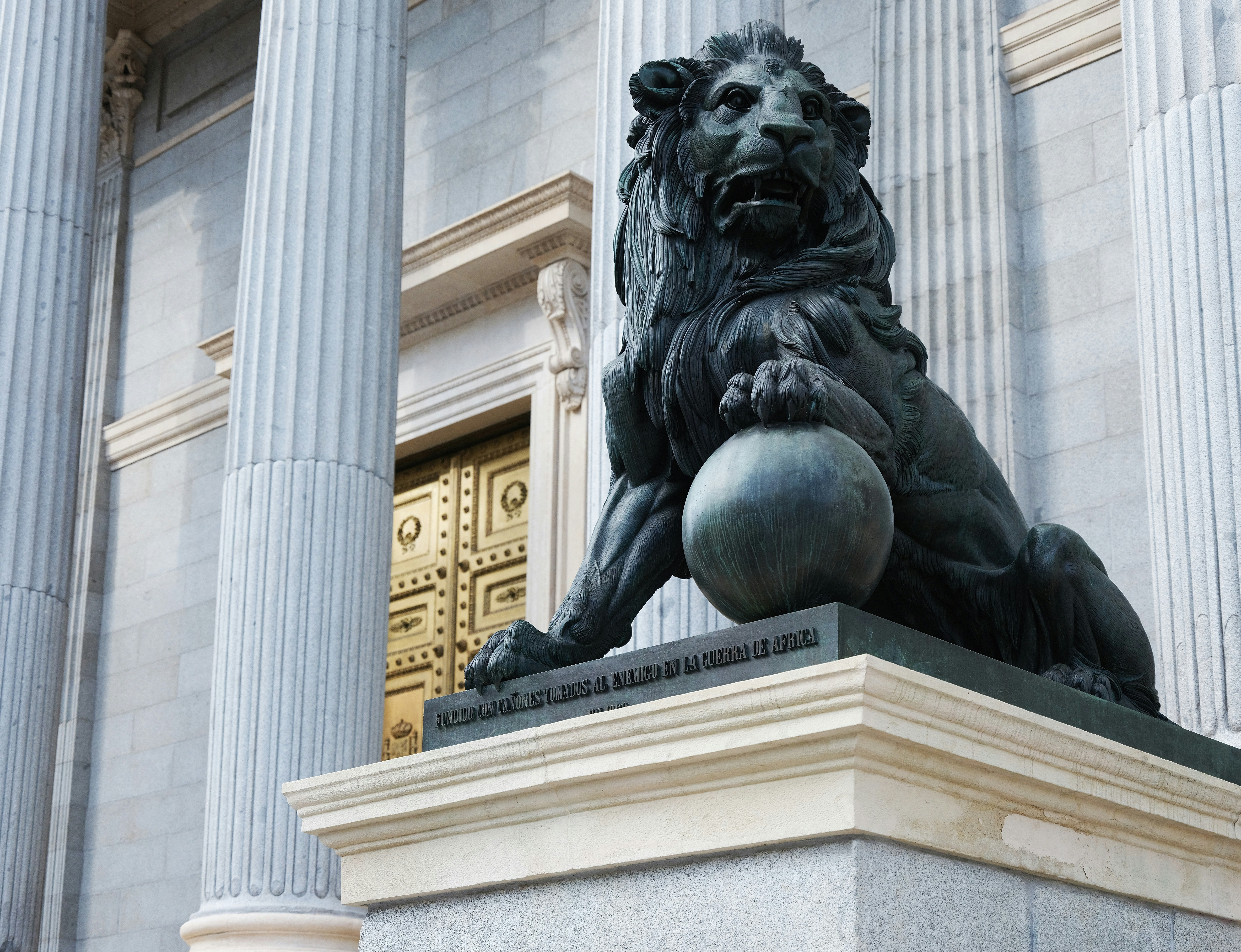 a statue of a lion holding a ball in front of a building, Monument of a Lion, Madrid, Spain