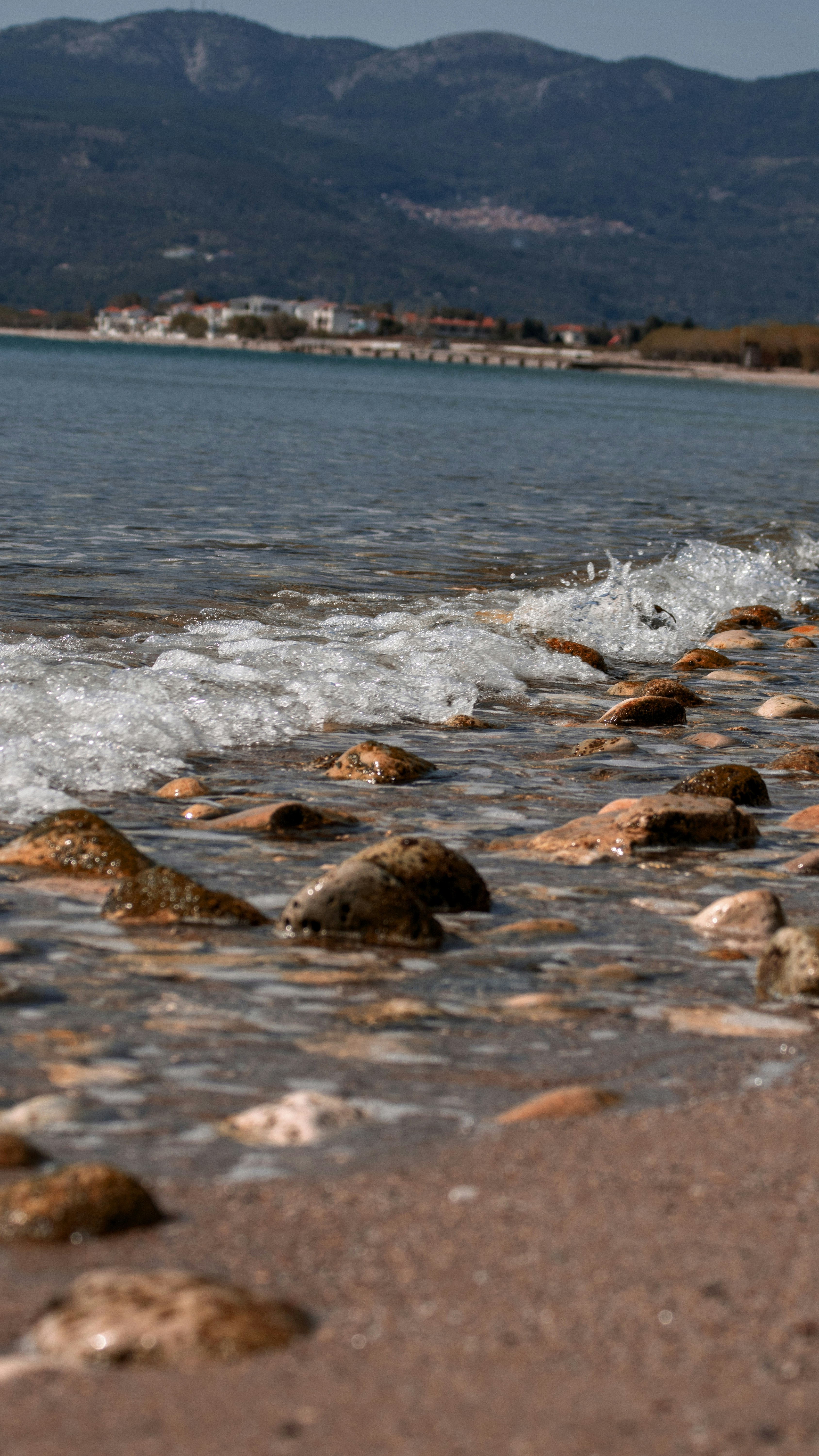 a beach area with rocks and water and mountains in the background